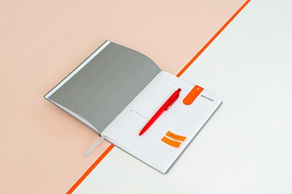 Szary notes z czerwonym długopisem i pomarańczowymi karteczkami