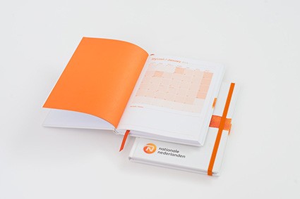 Otwarty notes z wkładką reklamową i pomarańczowym długopisem