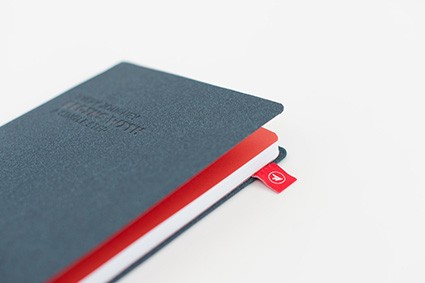 Granatowy notes z czerwoną metką i tłoczeniem na okładce